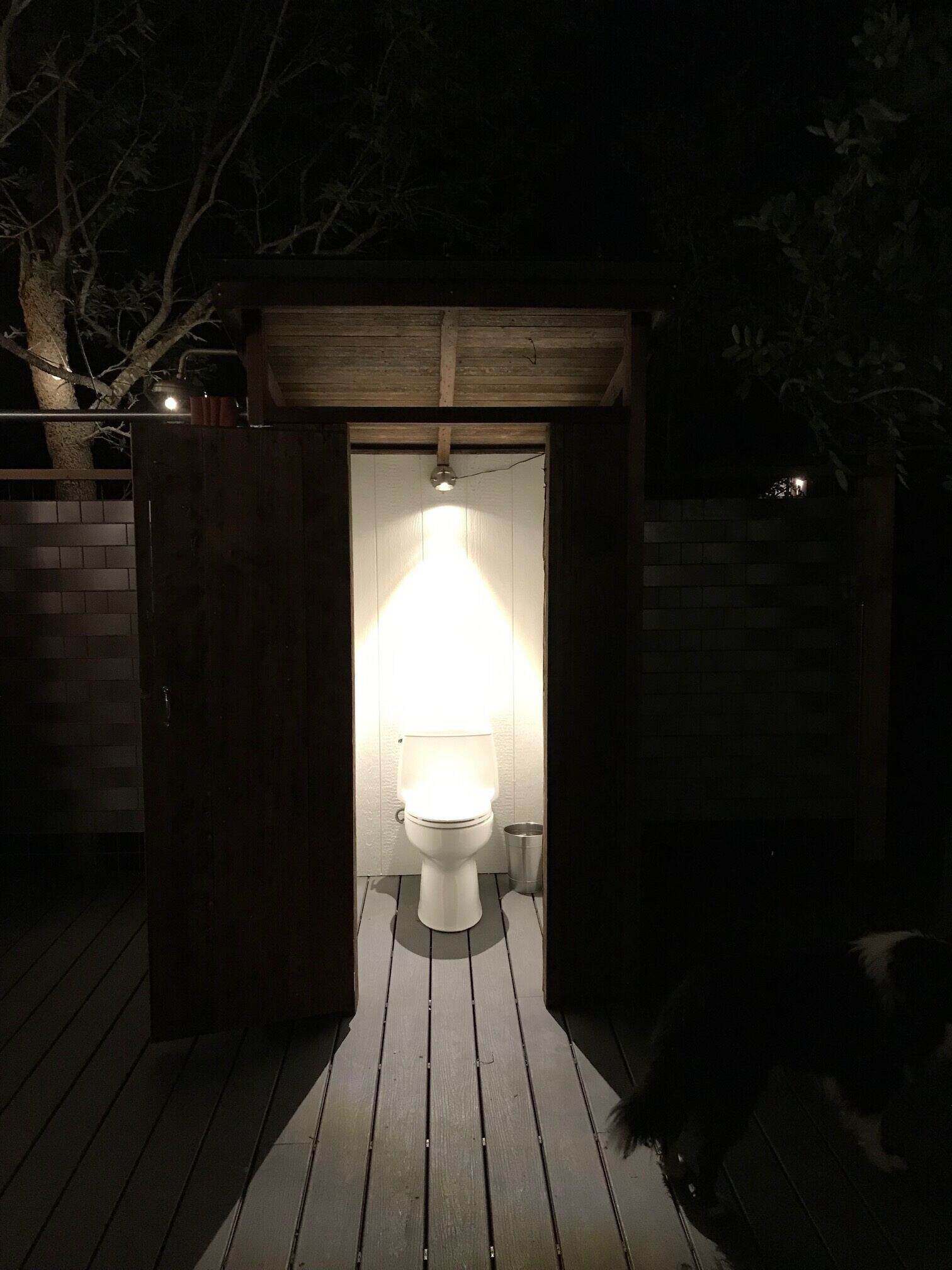 Outdoor restroom glowing at night with pendant light at Spencer Ranch cabin