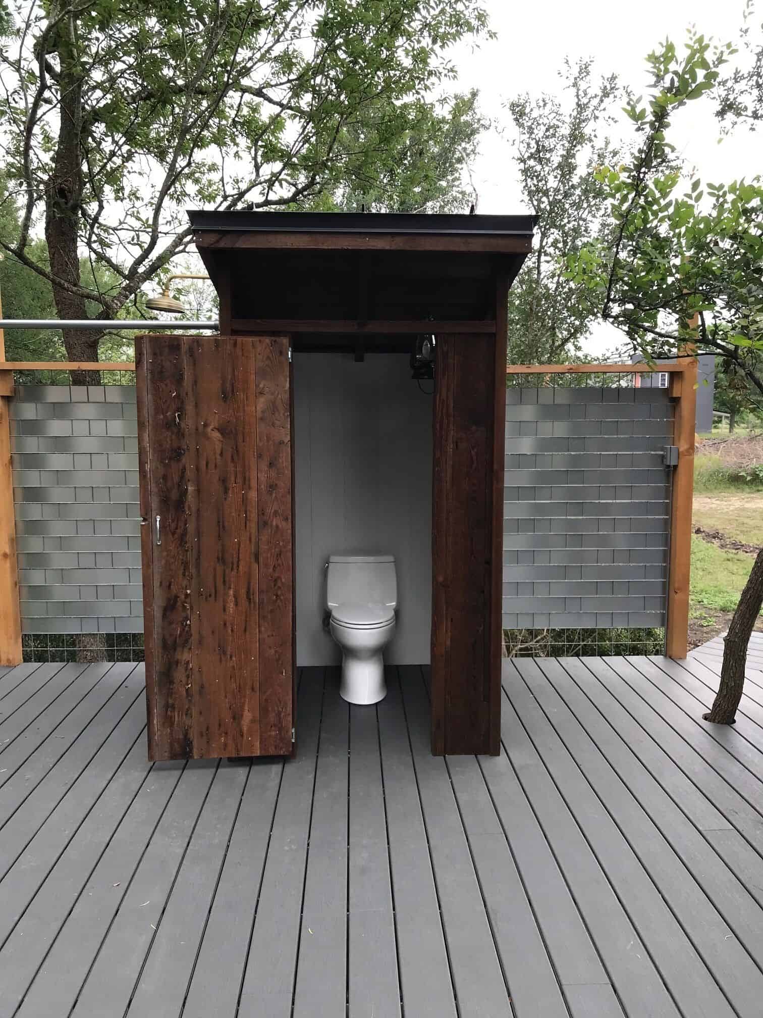 Outdoor restroom with reclaimed wood doors on the deck at Spencer Ranch