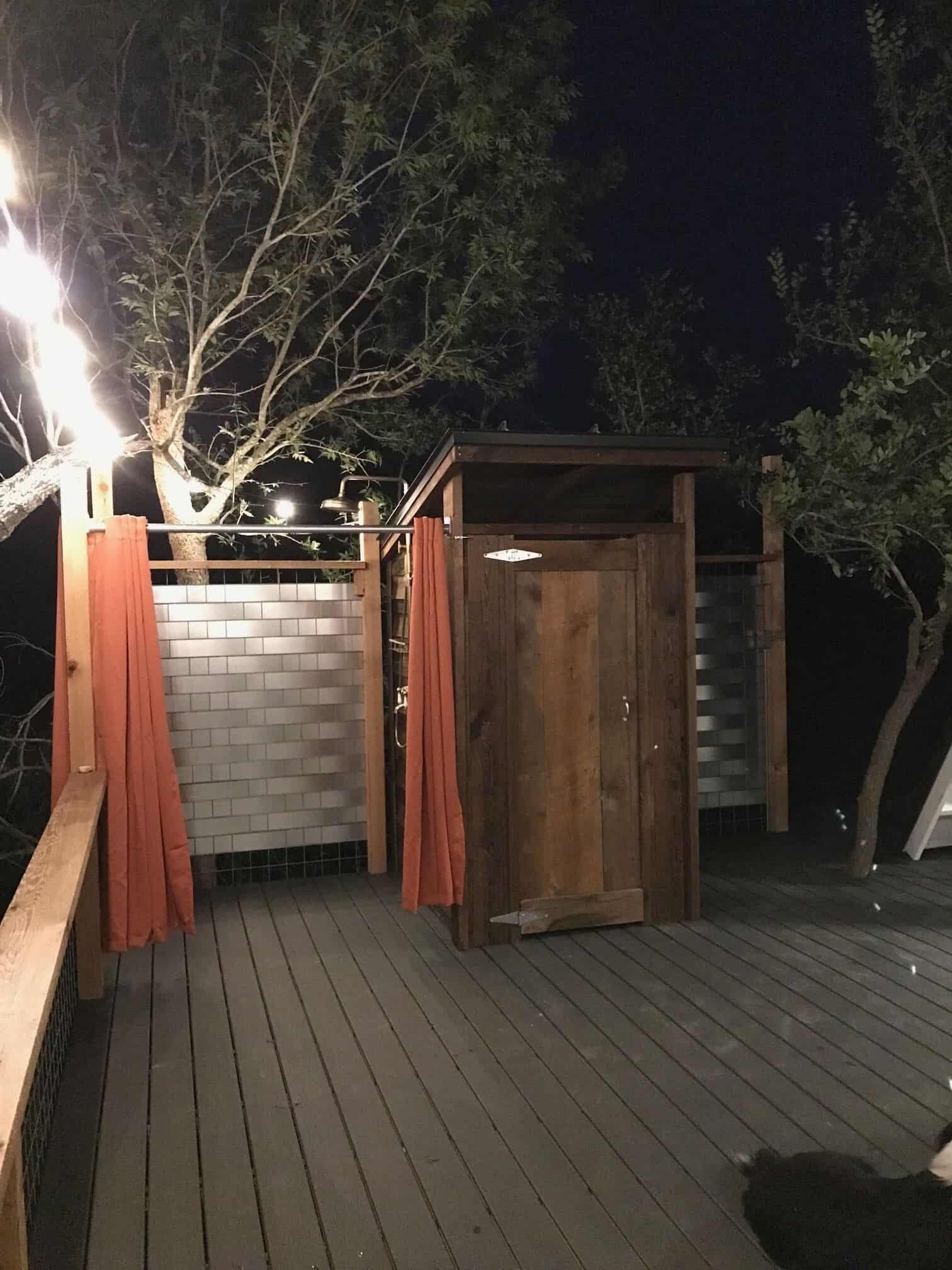 Outdoor shower at night with orange curtains and string lights at Spencer Ranch