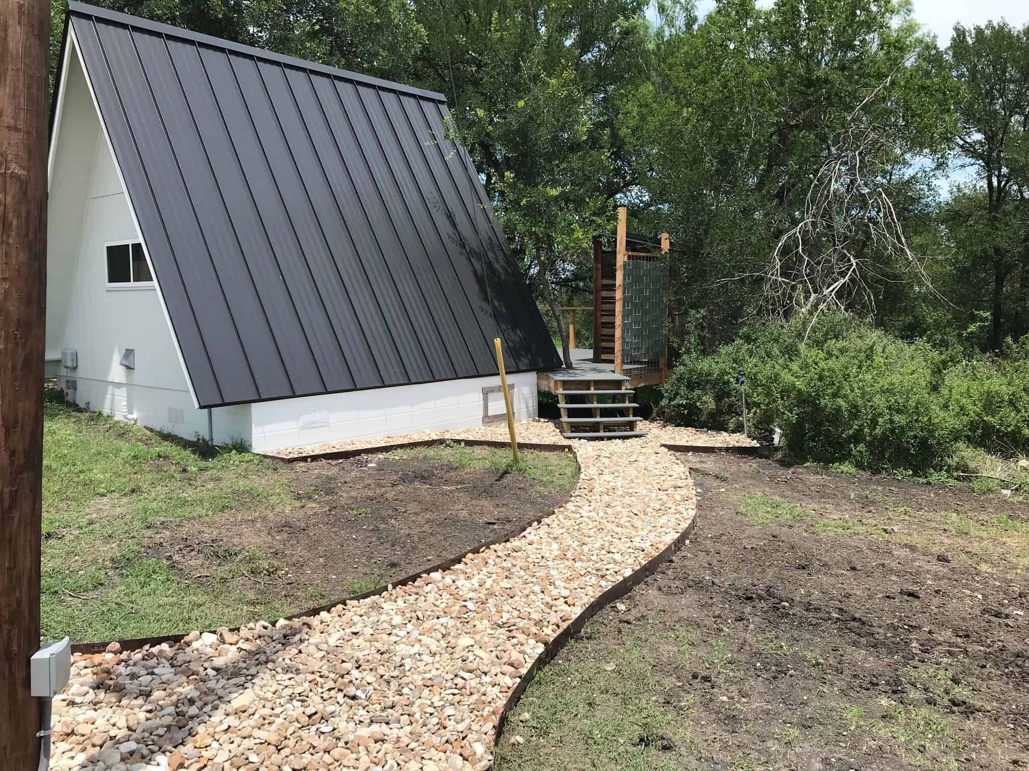 Side view of Spencer Ranch A-frame cabin with metal roof and gravel path to deck