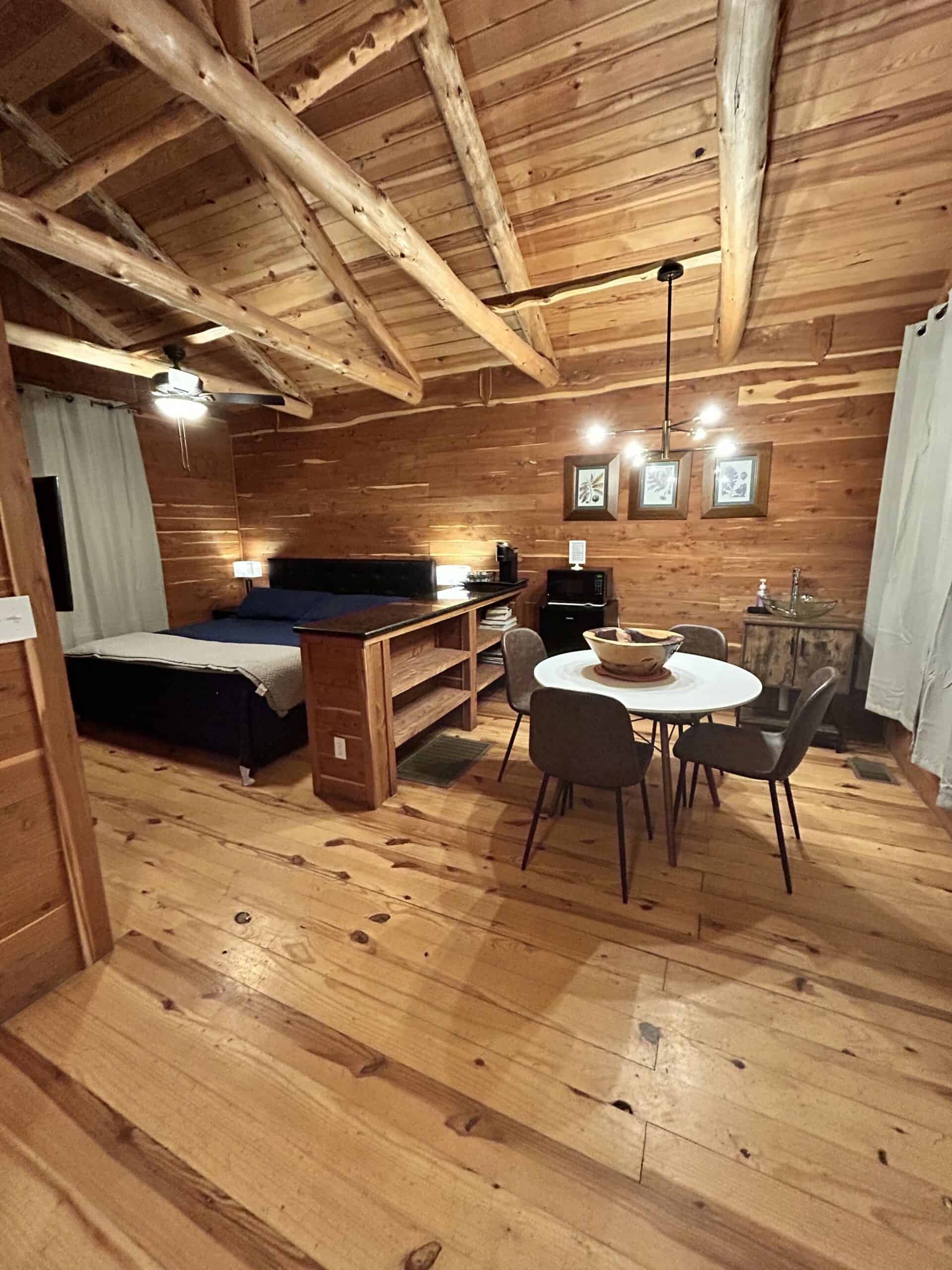 The Cabins at Angel Springs Woodland interior with king bed, exposed beam ceiling, and warm wood walls
