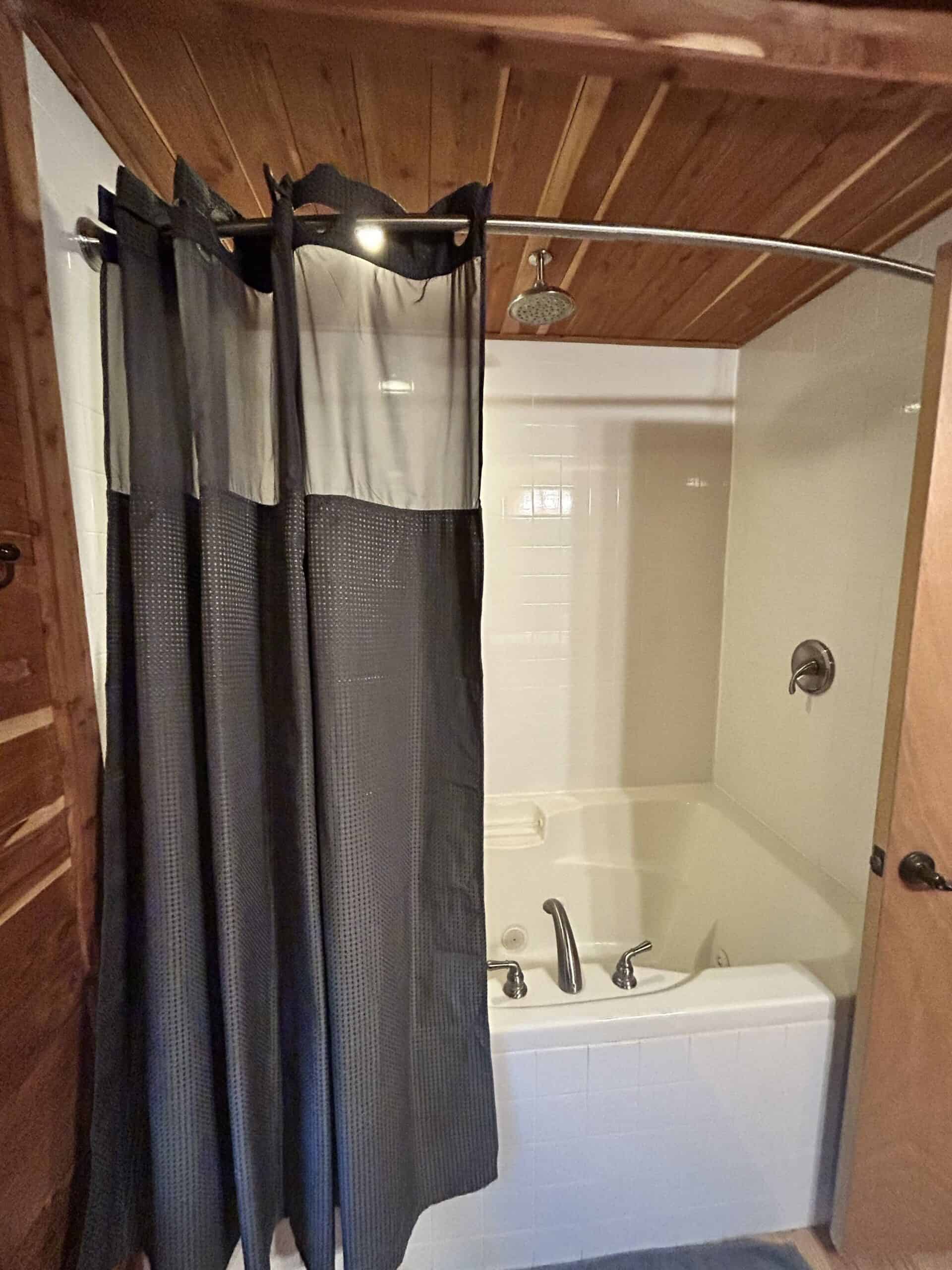 Jetted soaking tub with rainfall showerhead and wood ceiling at The Cabins at Angel Springs