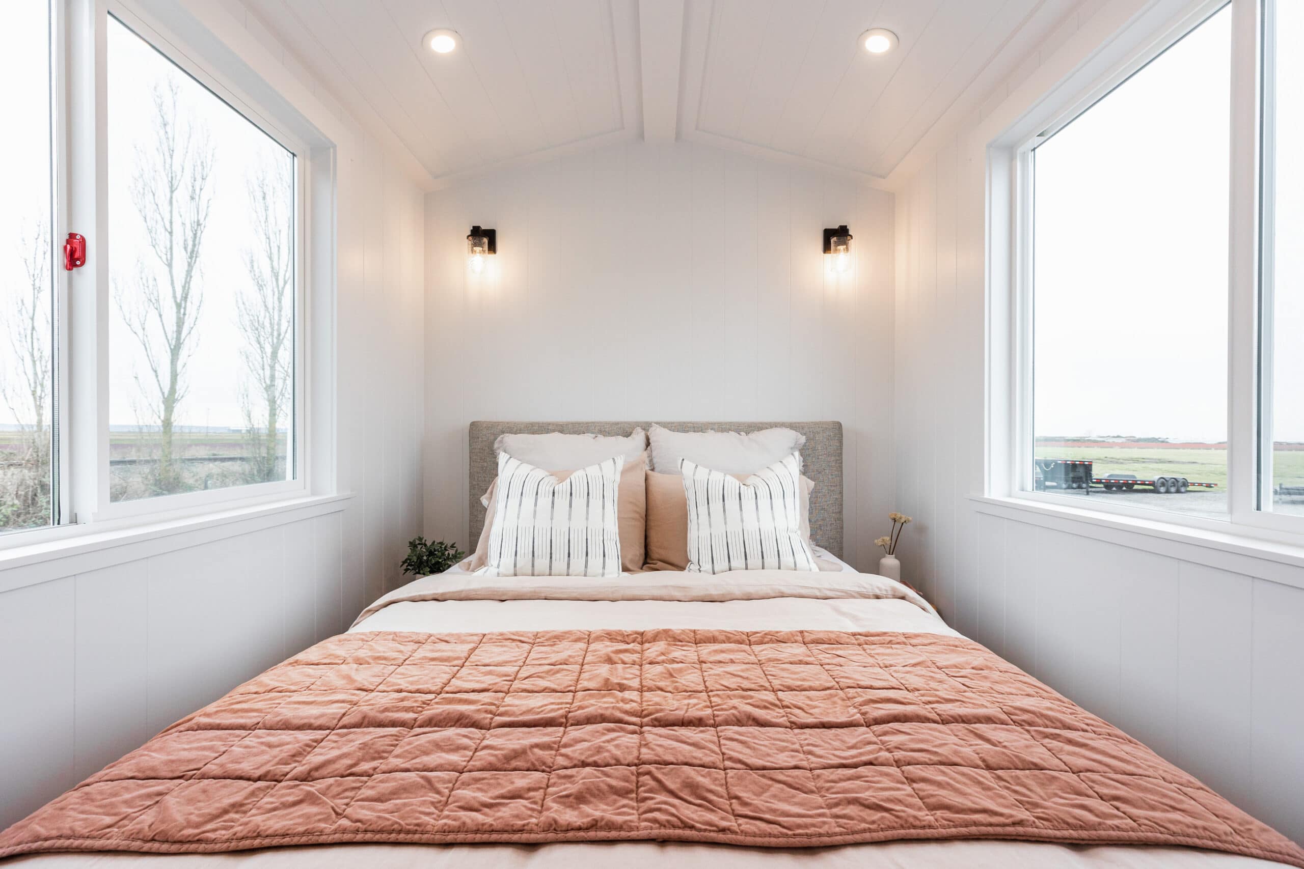 Bright tiny bedroom with large windows and minimalist decor for small space living.