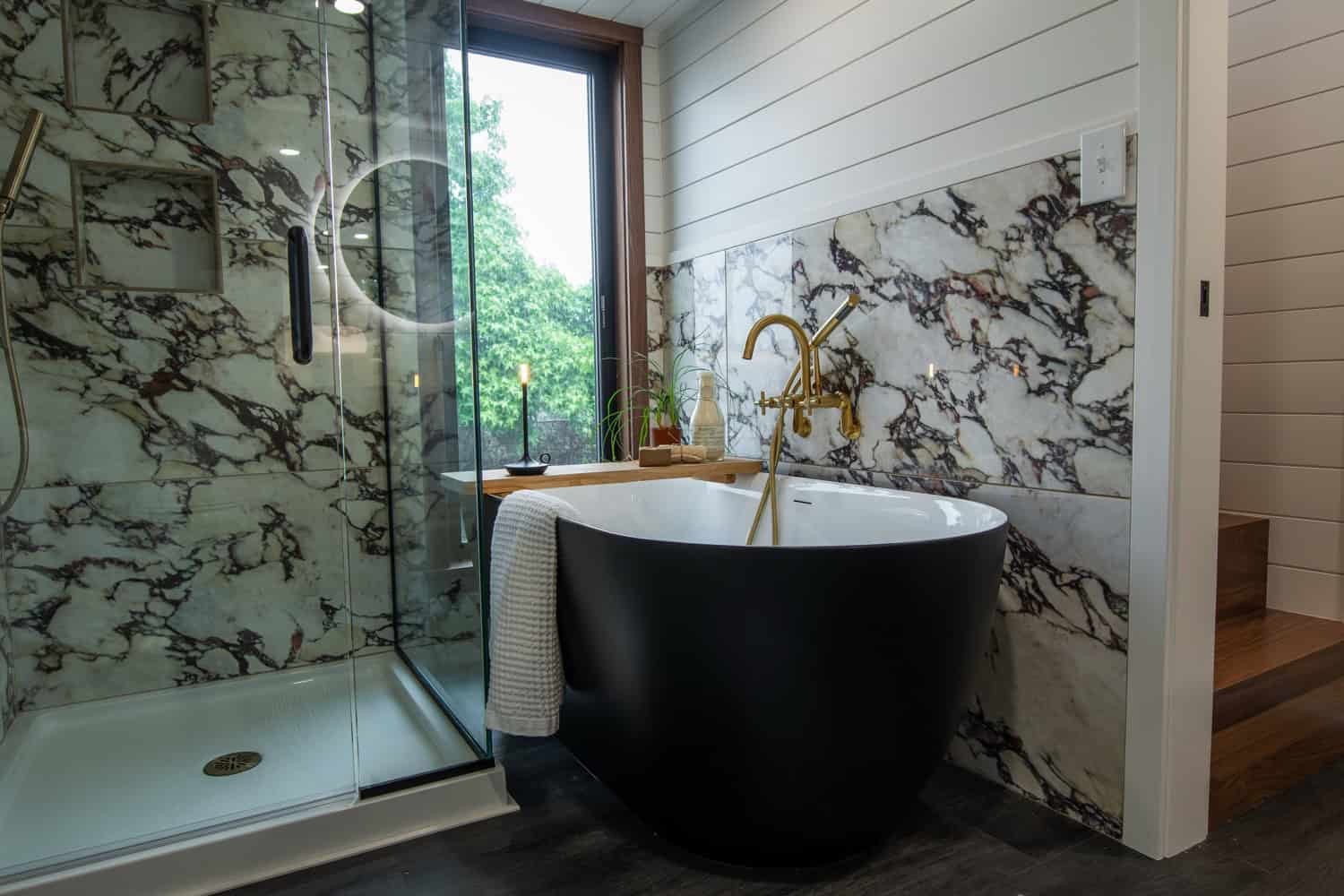 Wide view of the Cascade Max bathroom showing the marble shower, black tub, and walnut loft stairs