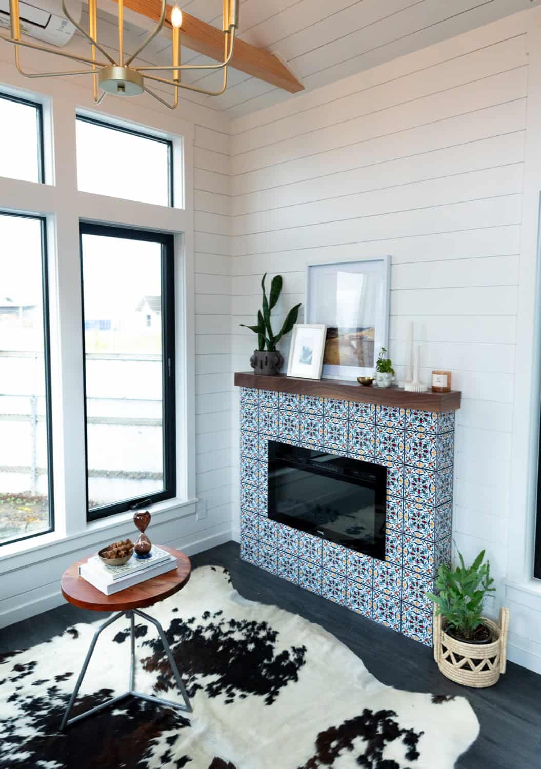 Living room fireplace with a patterned blue-and-white tile surround and walnut mantel in the Cascade Max