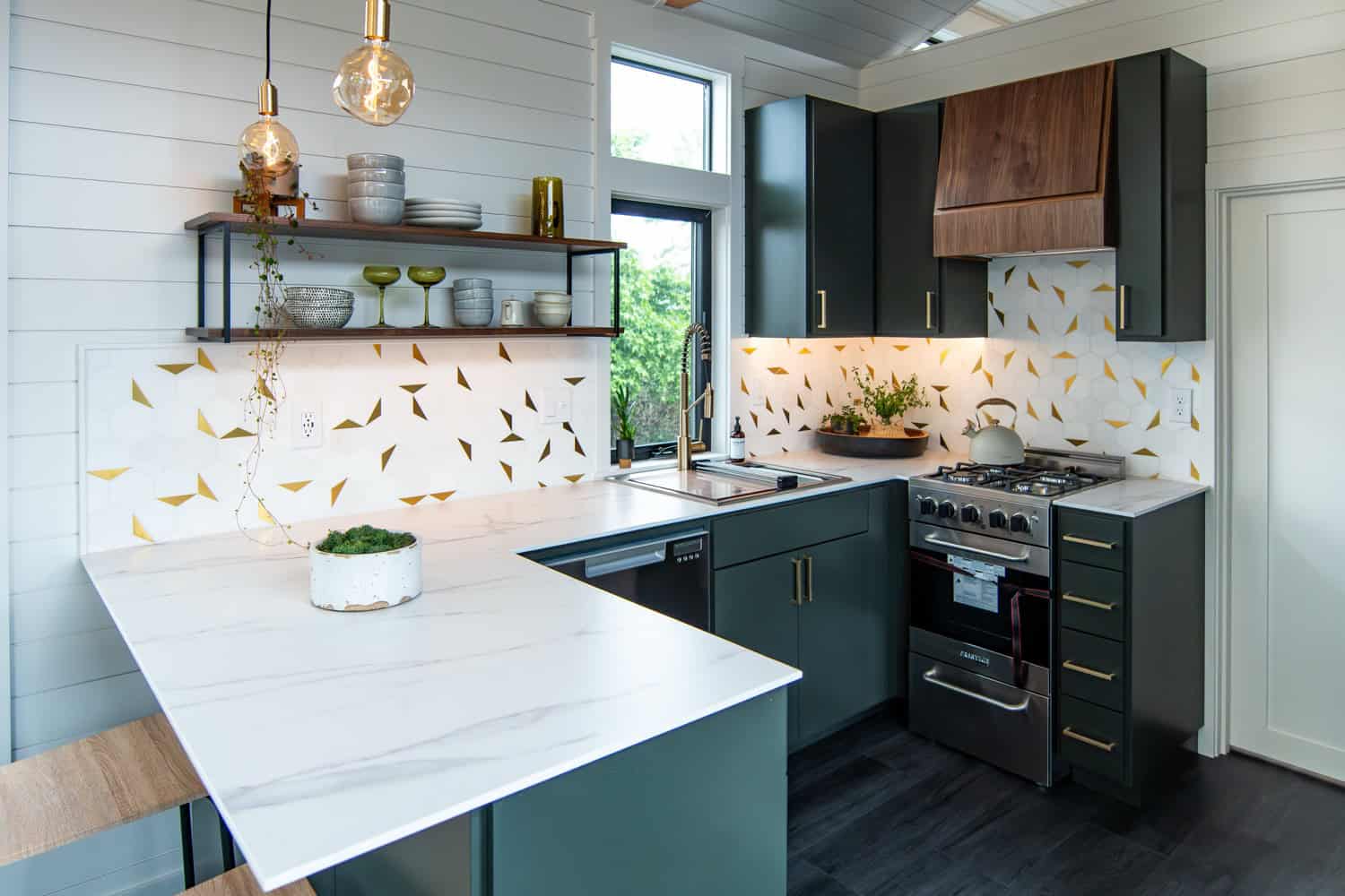 Cascade Max kitchen peninsula with marble-look waterfall counter, brass pendant lights, and open walnut shelving