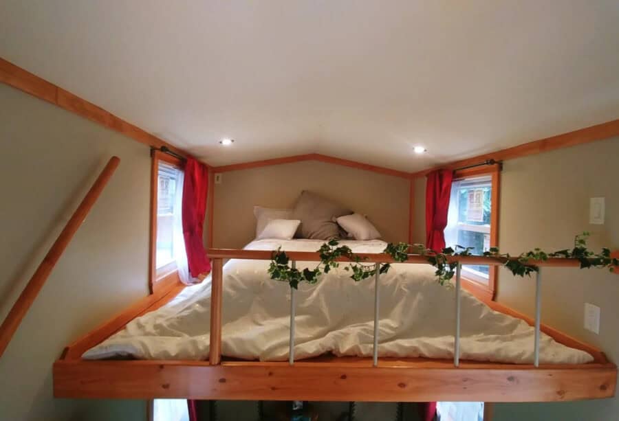 Cozy tiny house loft bedroom with bed and natural light.