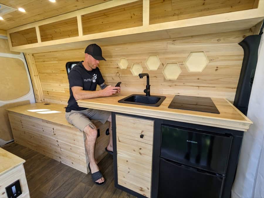 Compact tiny house kitchen with wooden accents and modern appliances.