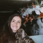 Woman enjoying her tiny van home with floral decor, embracing freedom in small spaces.