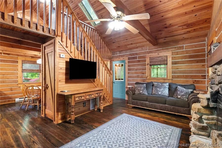 Rustic log cabin living room with wooden walls, ceiling, and furniture, featuring a comfortable sofa.