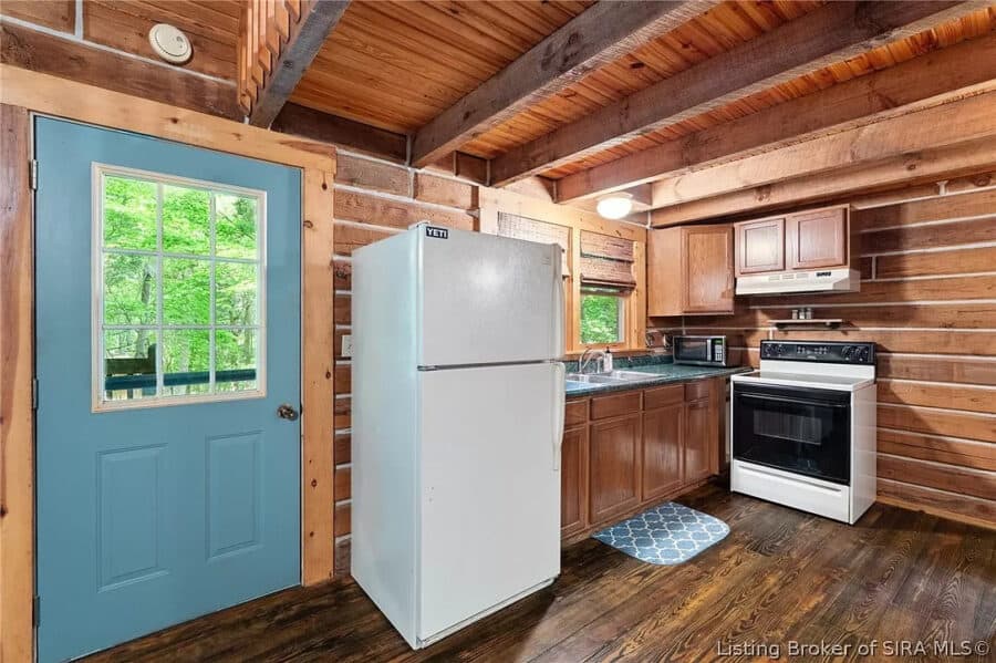 Compact kitchen inside a rustic log cabin near government land.