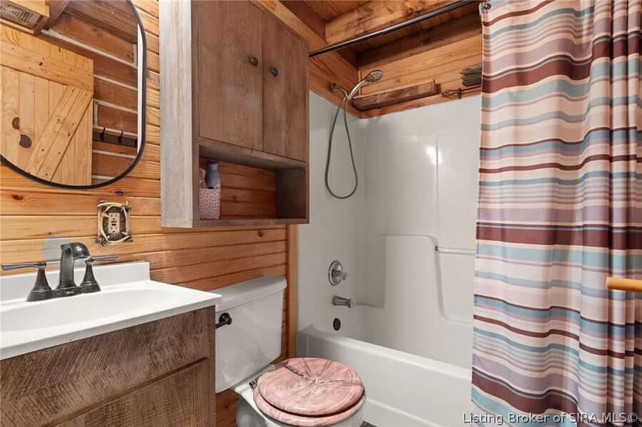 Rustic log cabin bathroom with shower, toilet, and wooden accents.