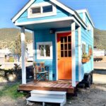 Charming 16-foot tiny house featuring a cozy front porch, perfect for minimalist living and maximizi.