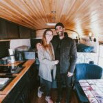 Interior of a converted school bus tiny house with cozy kitchen and seating area.