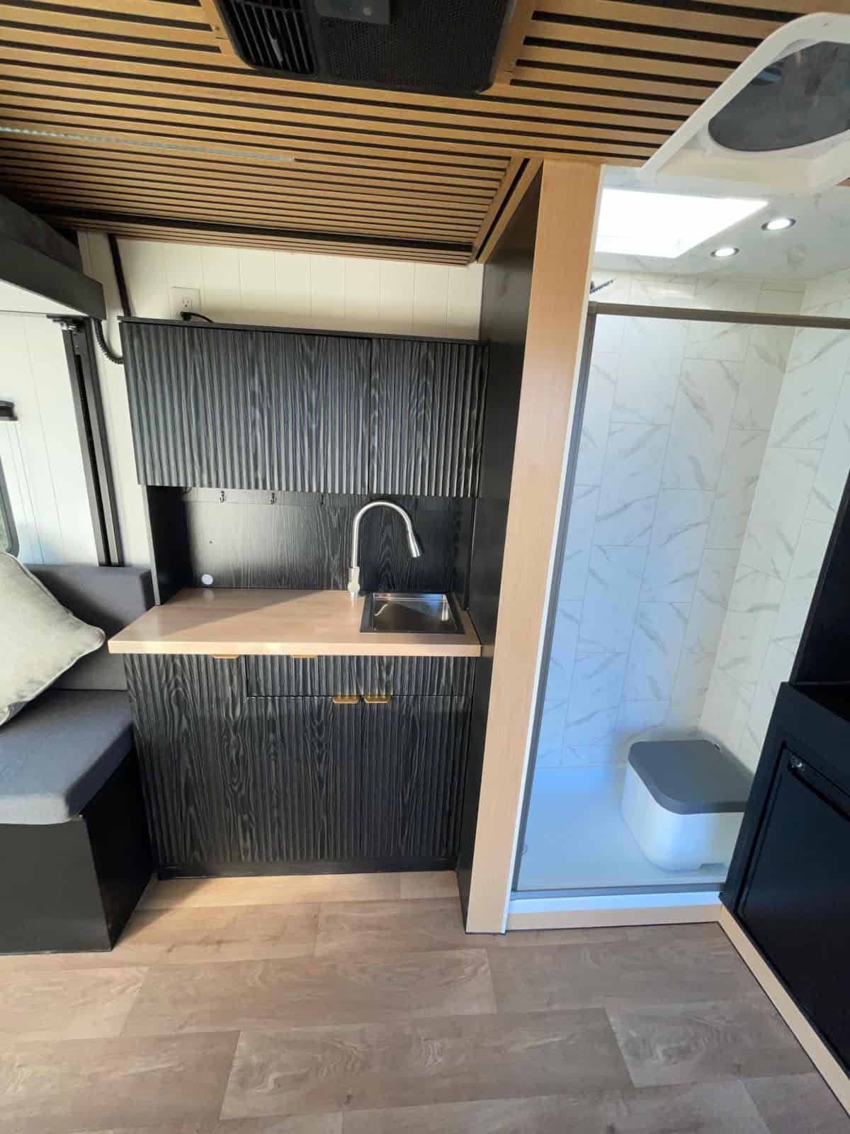 View of the kitchen counter and the glass-walled shower area inside the trailer