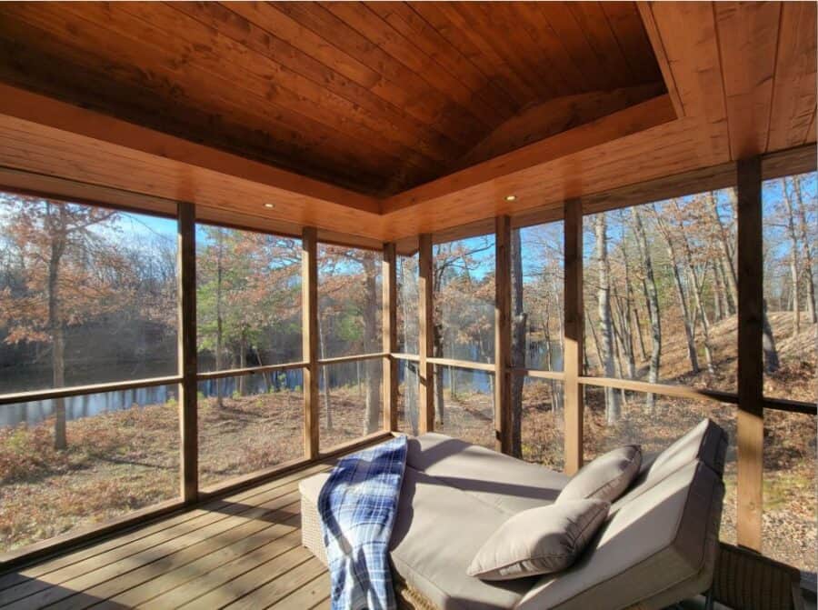 Bright screened porch with forest scenery and lake in the background, perfect for relaxing in a tiny.