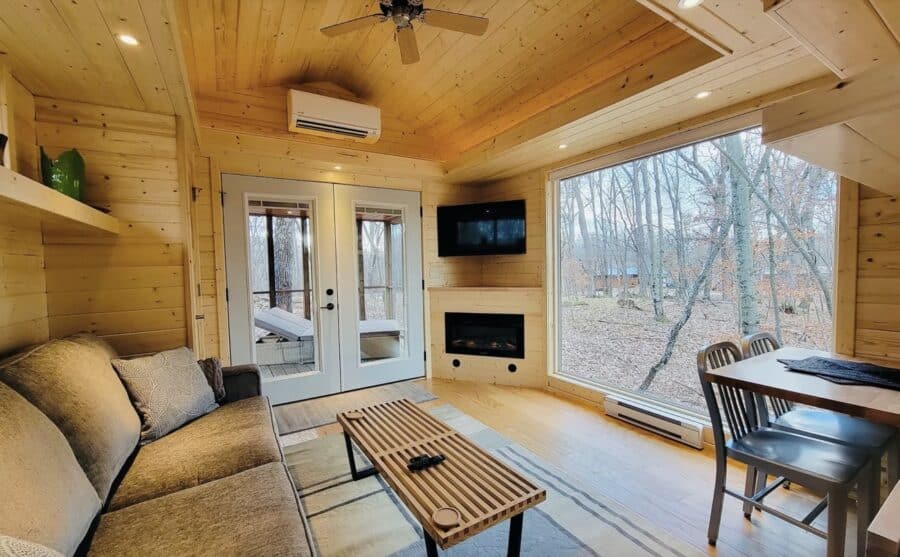 Bright tiny house interior with wood accents and large windows.