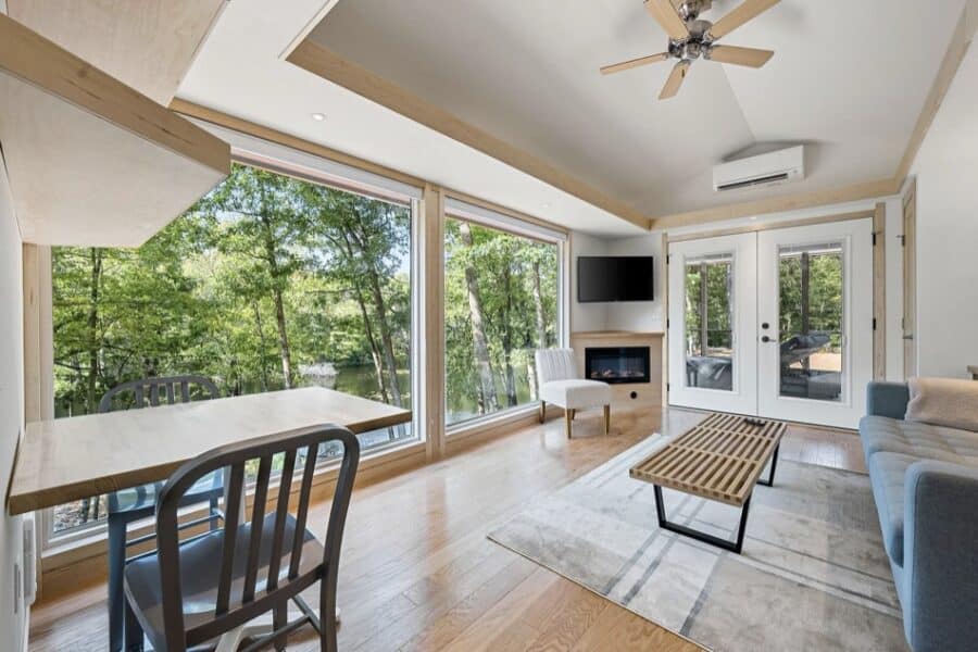 Bright and airy tiny house interior with large windows and modern furnishings.
