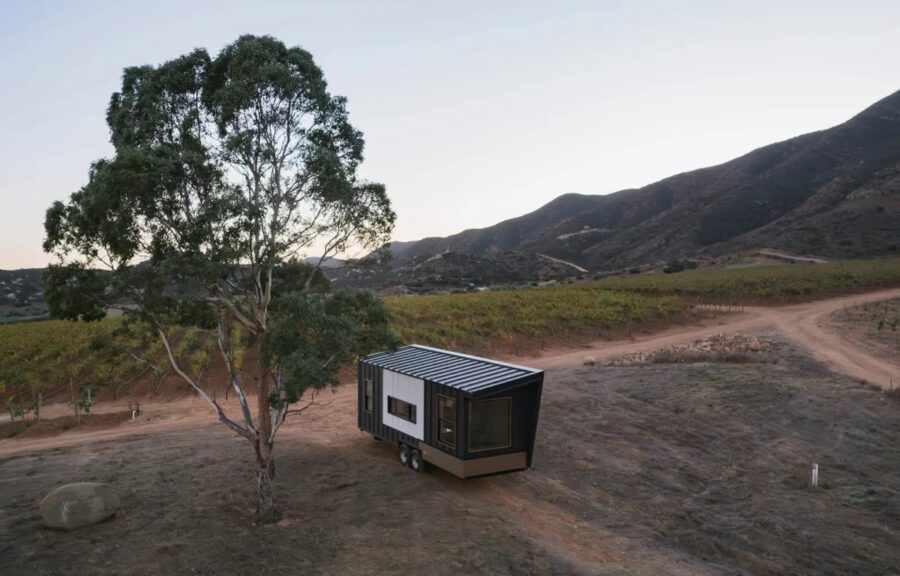 Clever S tiny house on wheels in a scenic outdoor setting with mountains and trees.