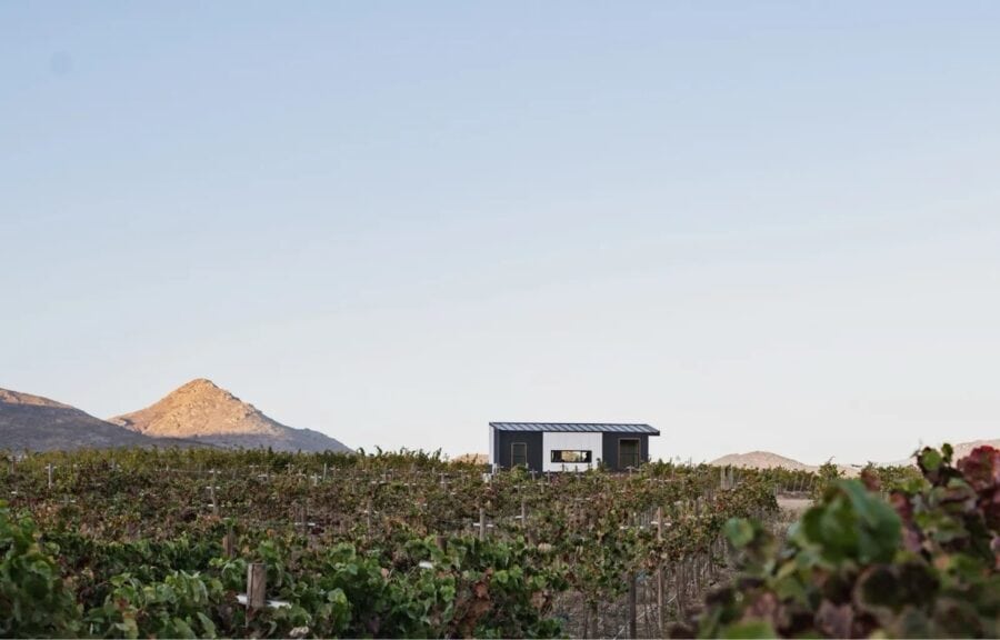 Tiny house in open countryside with mountains in the background.