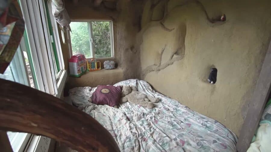 Bedroom with a plastered straw bale wall in the cob home