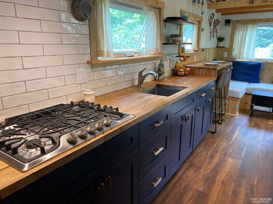 Charming tiny house kitchen with mountain siding, featuring navy cabinets, wooden countertops, and l.