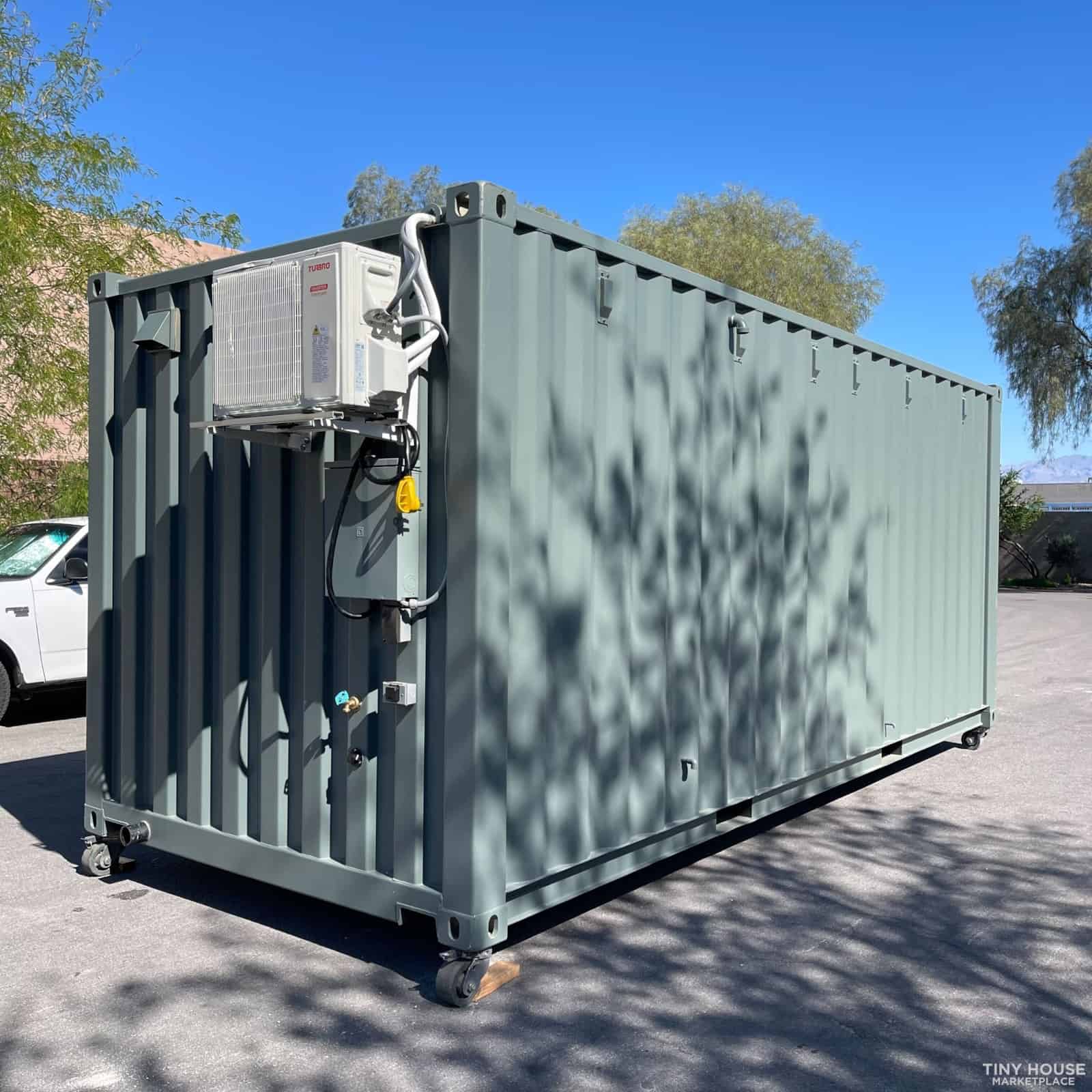 Large gray shipping container with cooling unit in outdoor parking area.