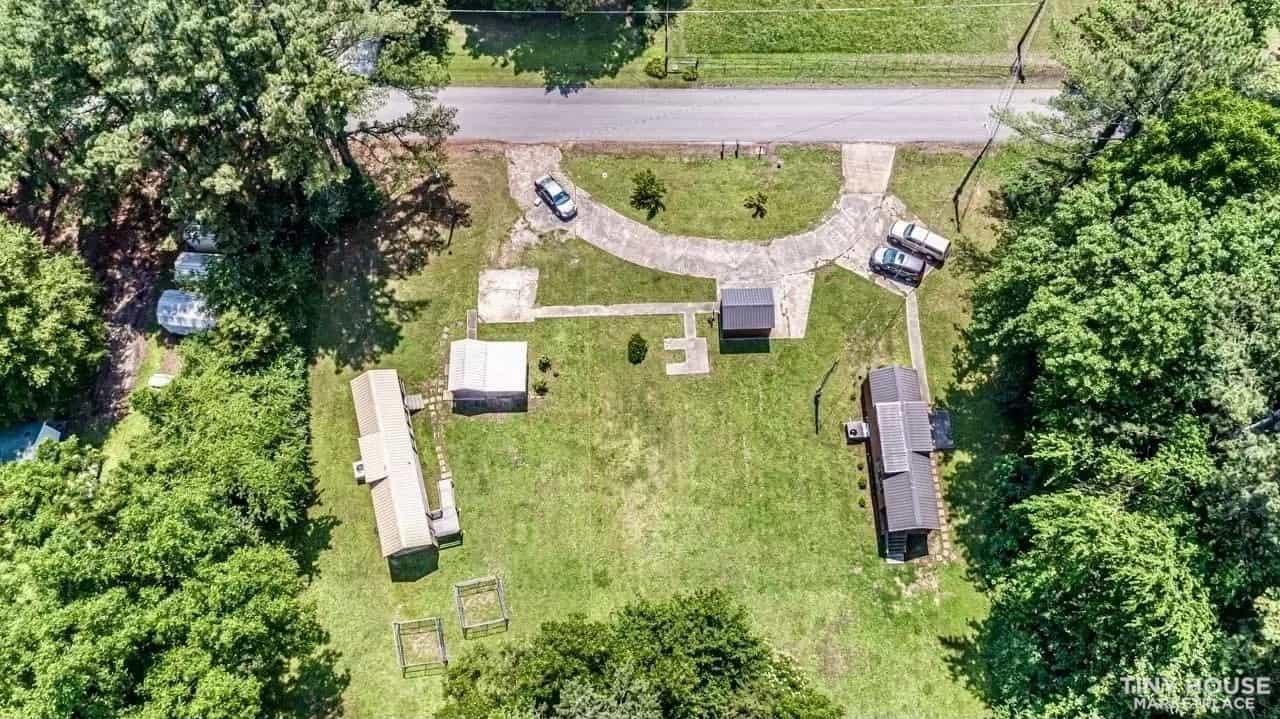 Aerial view of the three-acre Williston, Tennessee property showing the tiny home, storage building, driveway, and surrounding trees.