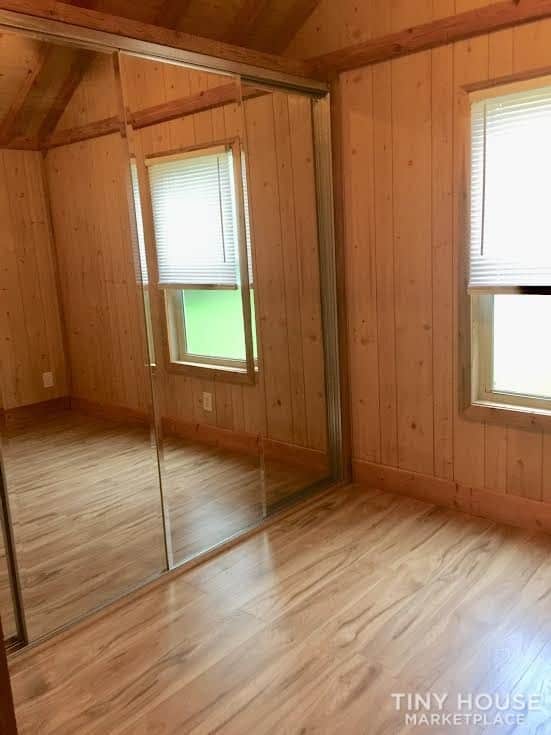 Main-floor bedroom of the Country Cottage with mirrored sliding closet doors, pine walls, and two windows.