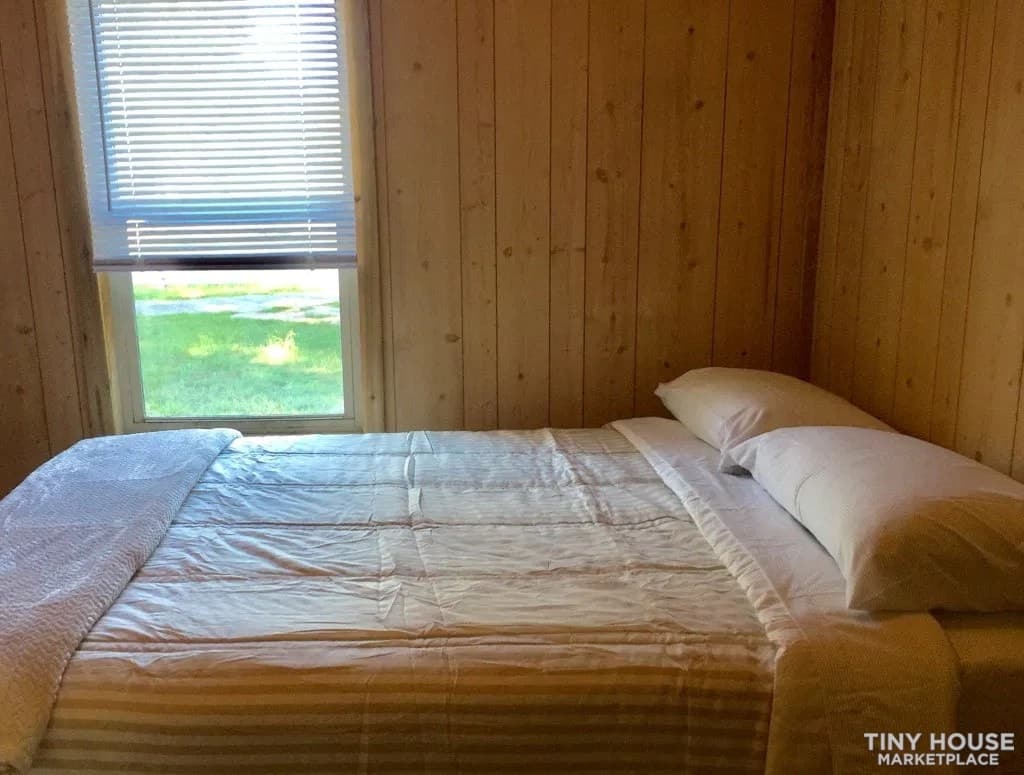 Queen bed beneath a window in the main-floor bedroom during the home’s time as a short-term rental.