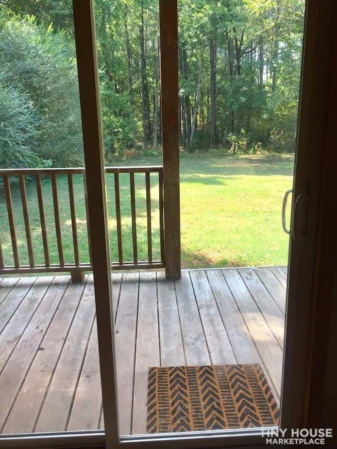 View through the sliding glass door onto the wood deck and the wooded lawn beyond.