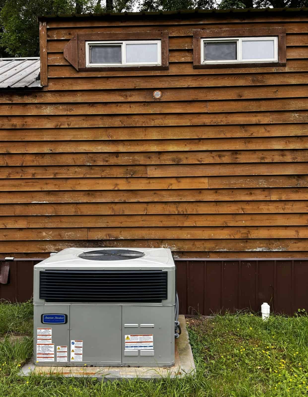 New two-ton HVAC condenser unit installed beside the cedar-sided exterior of the Country Cottage.