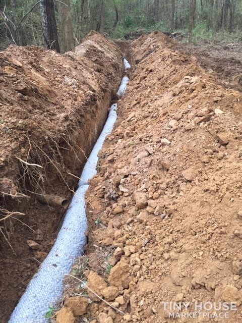 Freshly trenched septic field lines with new gravel and drain pipe on the three-acre property.
