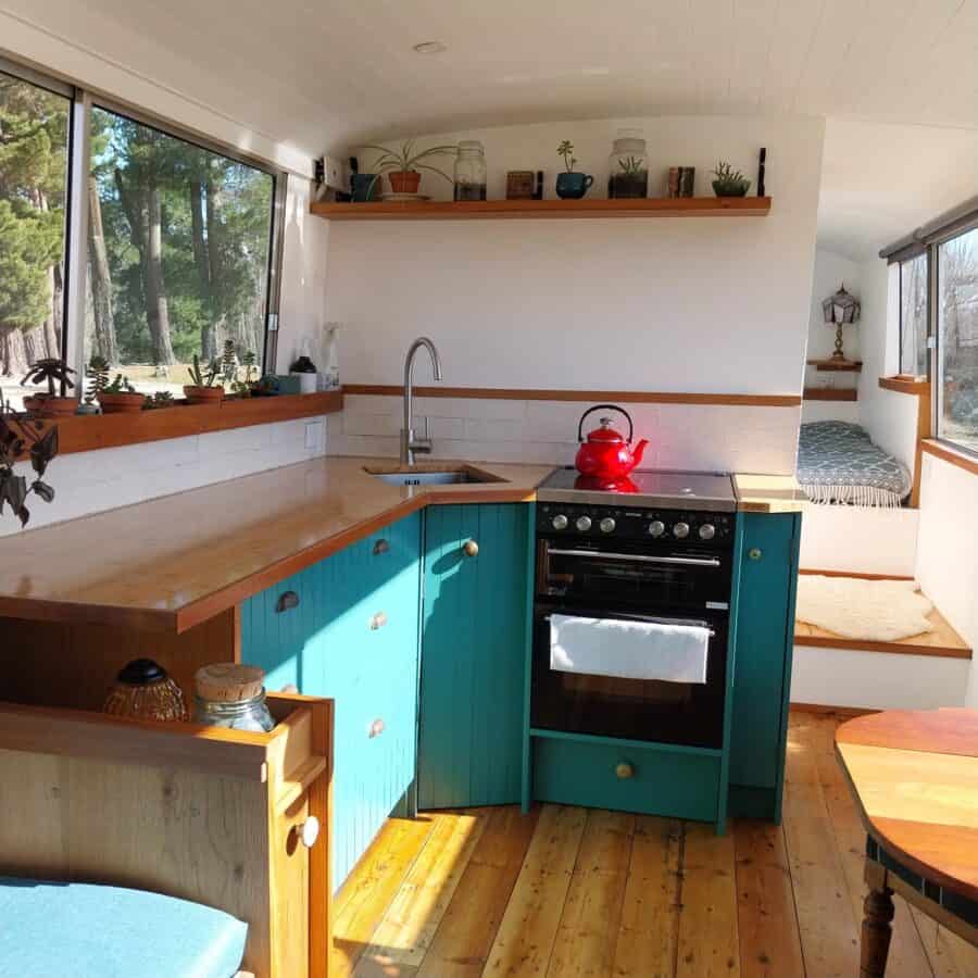 Small tiny house kitchen with bright blue cabinets and natural wood accents.