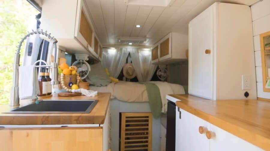 Cozy tiny house interior featuring a bed, kitchen area, and a colorful parrot perched nearby.