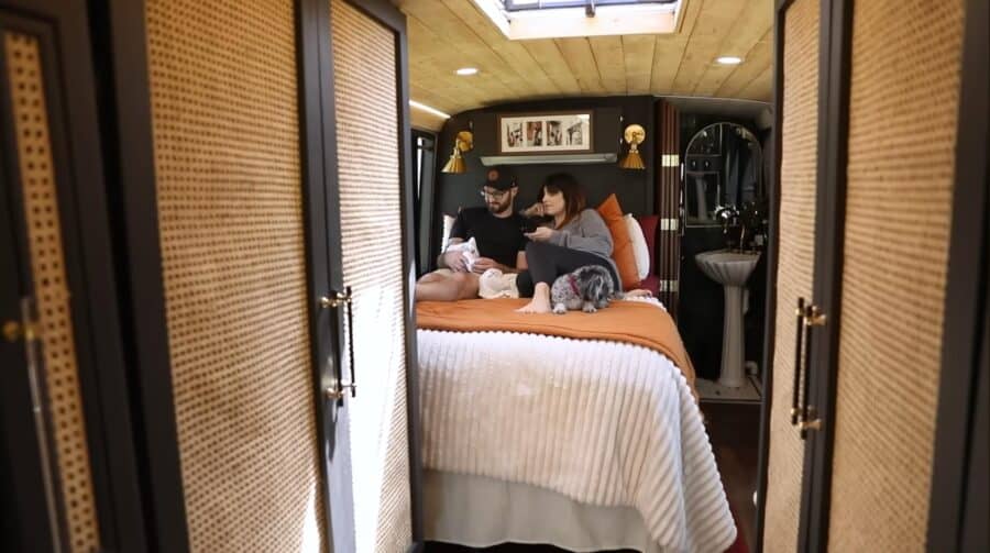 Cozy tiny house interior with a couple and newborn on the bed.