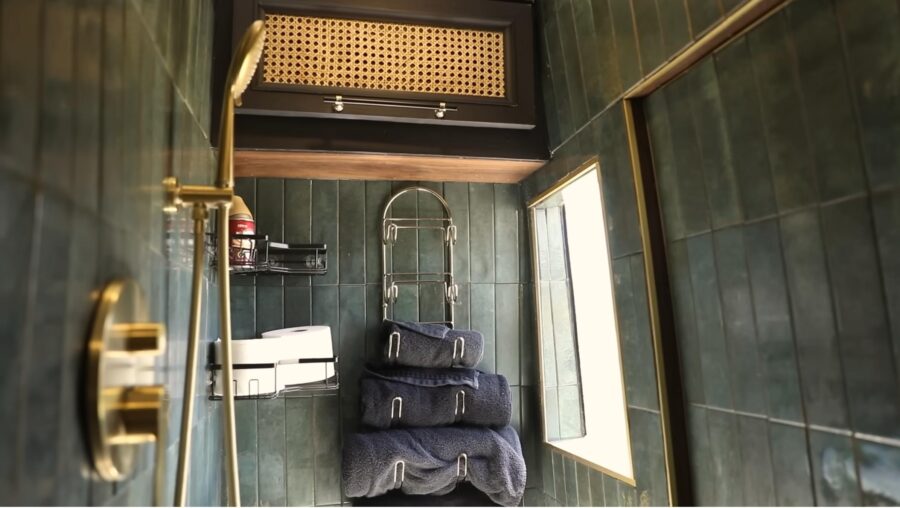 Compact bathroom with towel storage and small window in a tiny house.