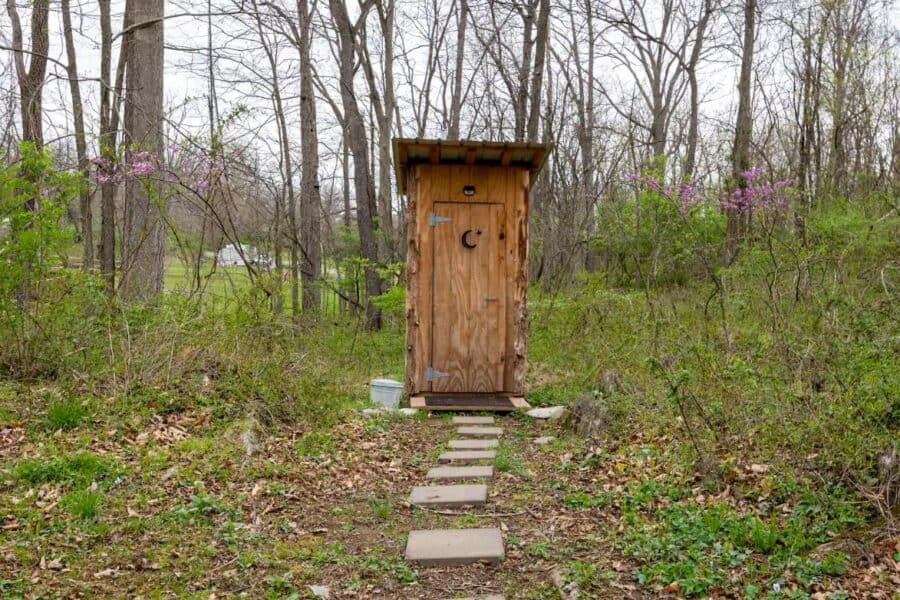 Small wooden tree house in a forest setting with a stone pathway.