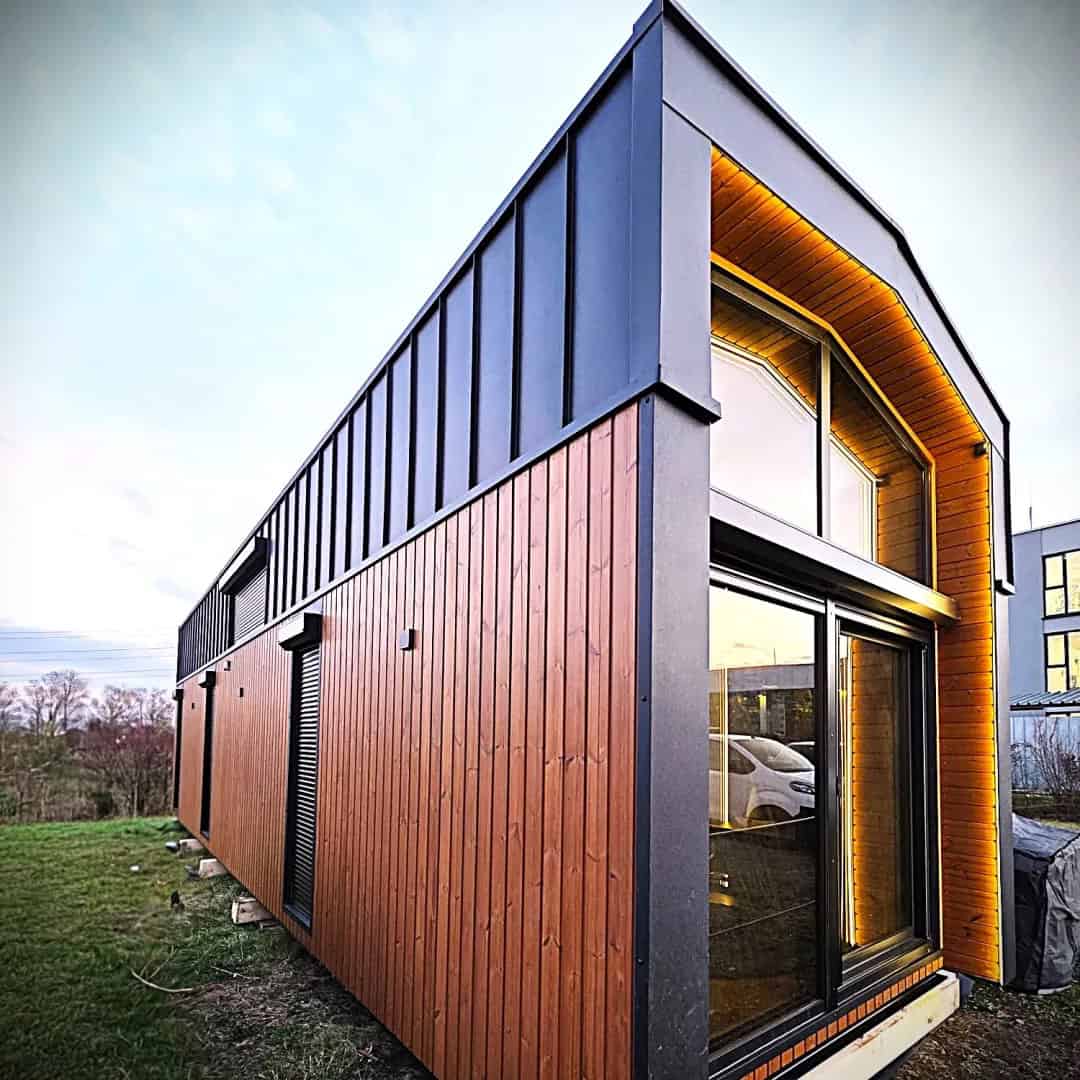 Jake flagship modular house by Craft House with an arched glass gable end, wood cladding, and charcoal standing-seam metal