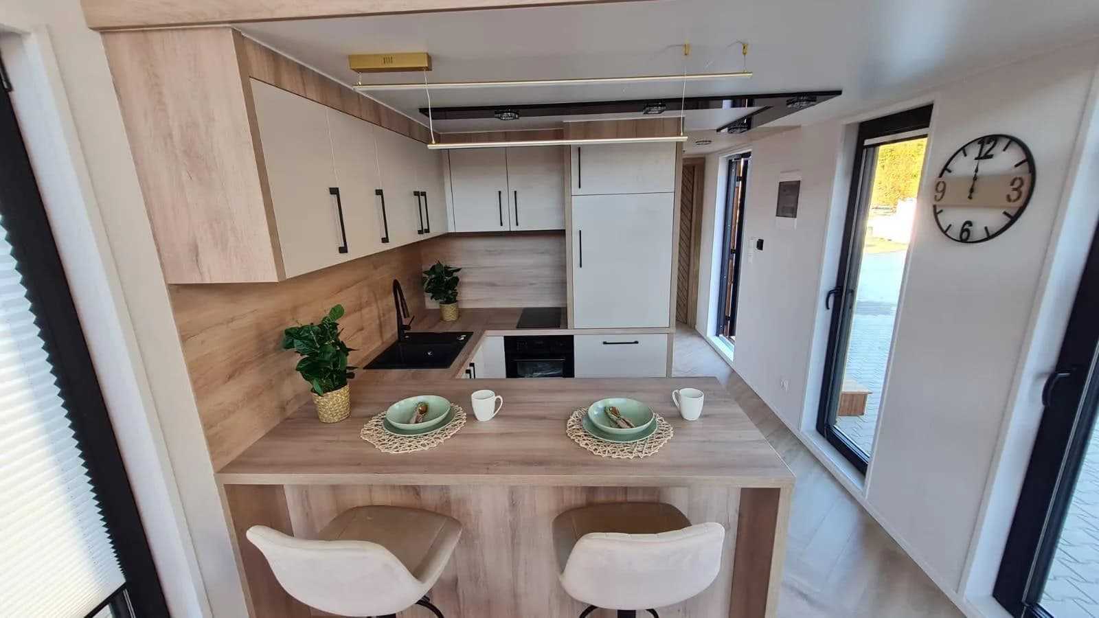 Two-tone island kitchen in the Lukas modular house with induction hob, oven, and a wood breakfast bar