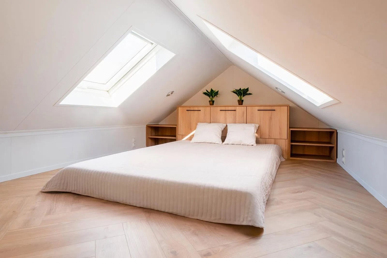 Skylit mezzanine bedroom under the gable roof of the Lukas modular house with roof windows and herringbone floor