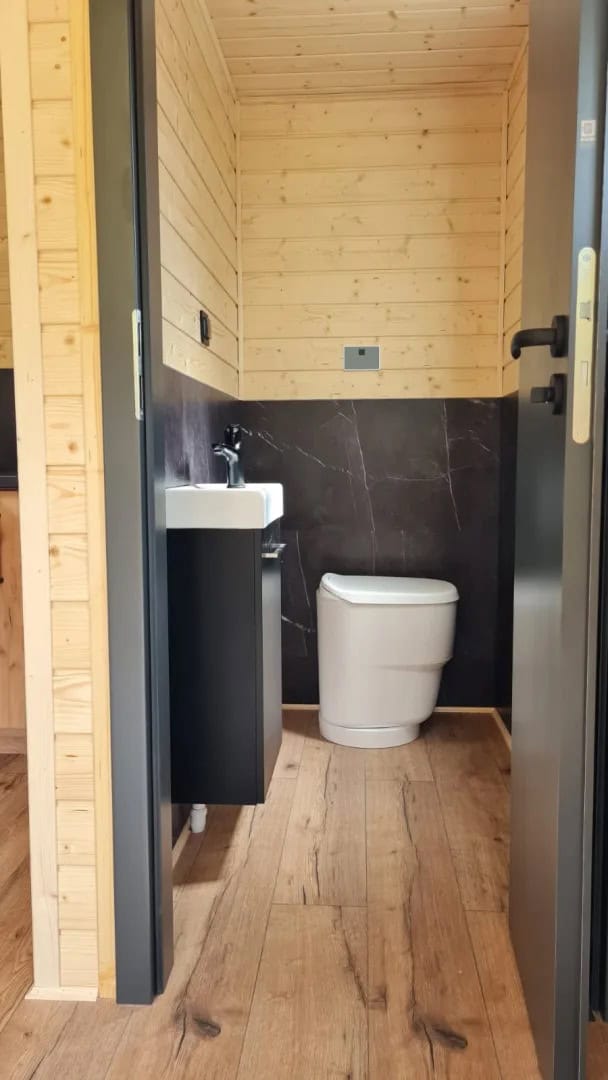 Compact bathroom with toilet and washbasin vanity inside the Off-Grid Craft House tiny house