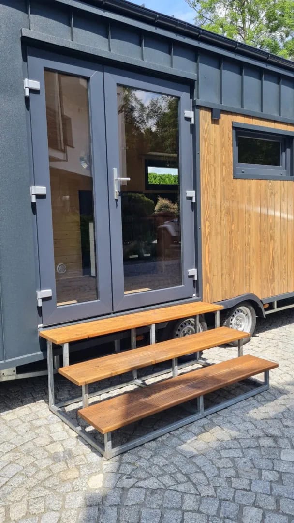 Glass double-door entry with wooden step bench on the Off-Grid Craft House