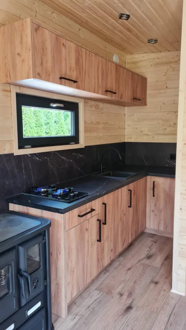 L-shaped kitchenette with gas cooktop, black counter, and wood cabinets in the Off-Grid Craft House