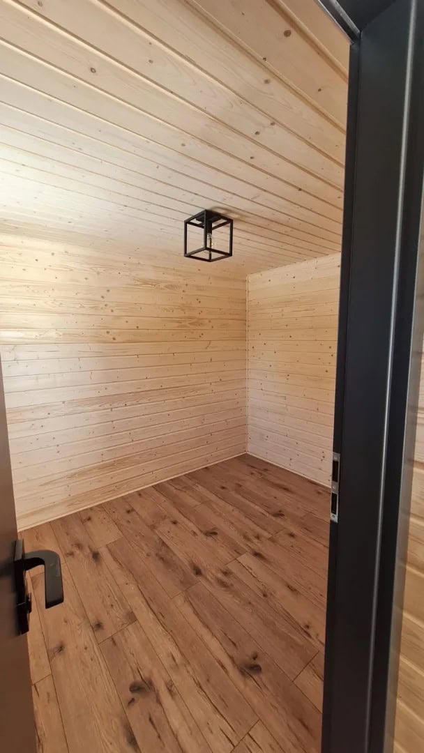 Private ground-floor bedroom in the Samuel modular house lined in warm spruce with a wood floor