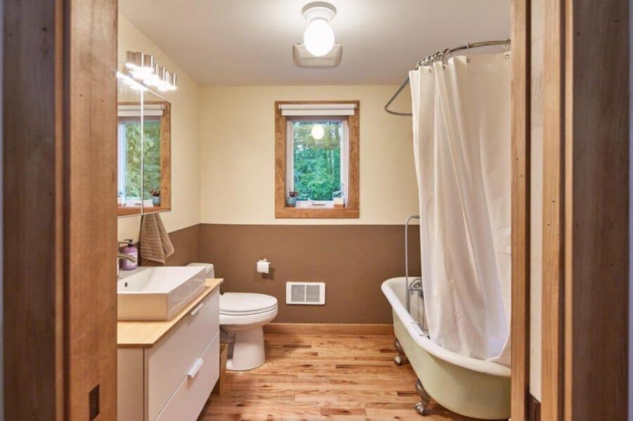 Cozy tiny house bathroom with clawfoot tub, wooden accents, and natural light.