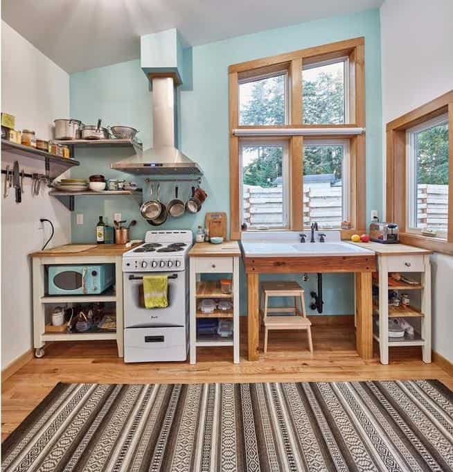 Bright tiny house kitchen with natural light and functional wooden countertops.