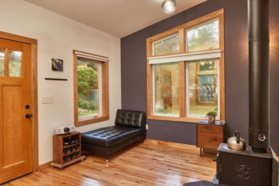 Bright interior of a tiny house with large windows and modern decor.