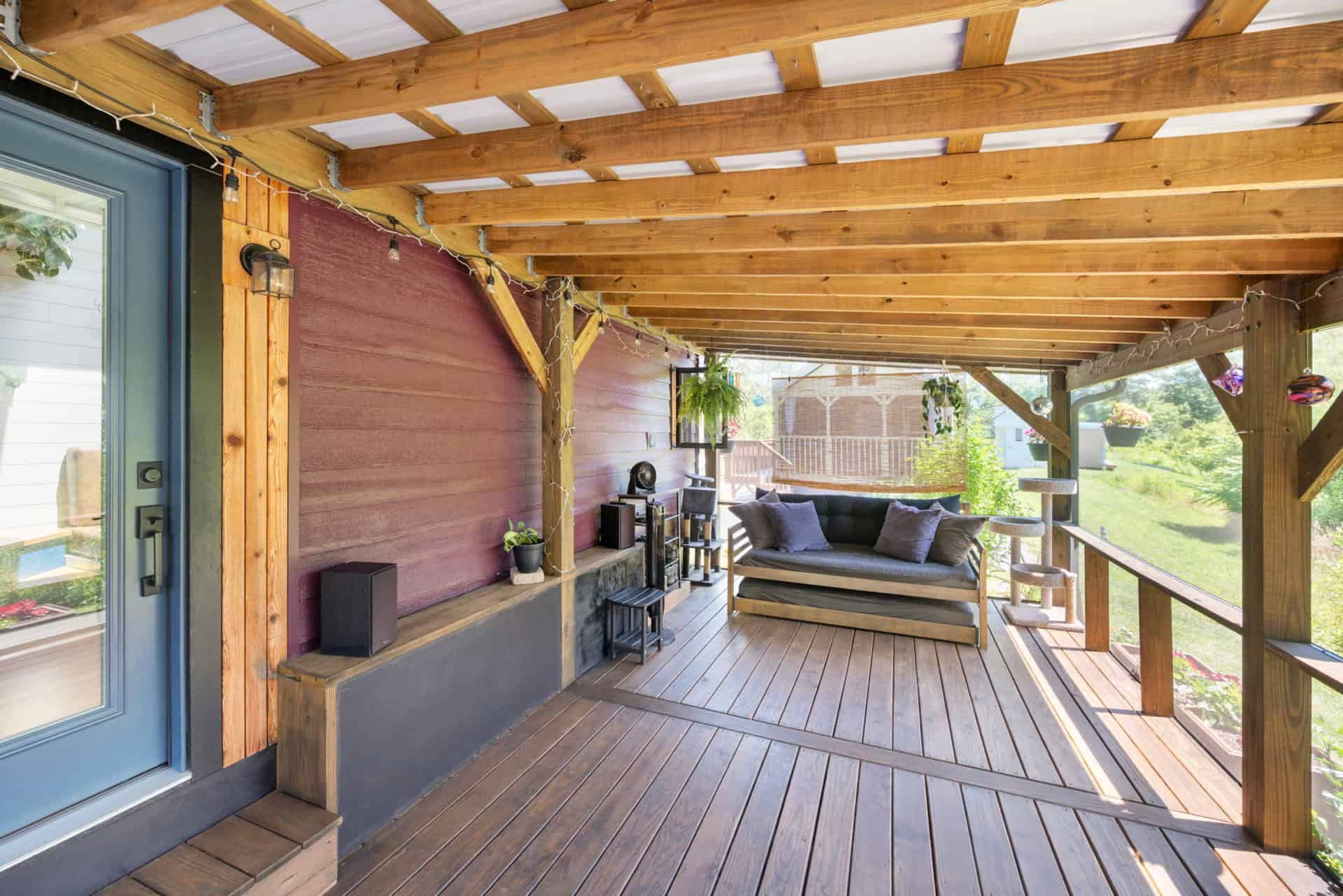 Large covered timber-framed porch with daybed and deck seating