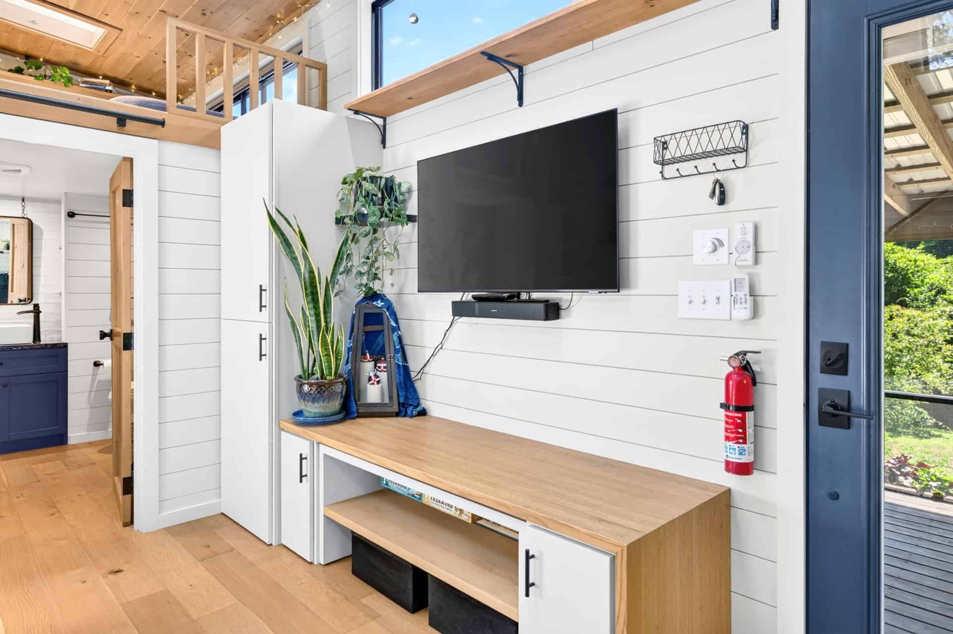 Navy blue tiny house kitchen with farmhouse sink, quartz counters, and gas range